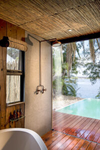 Ducha abierta con vistas al río Zambezi en Thorntree River Lodge, alojamiento de lujo sostenible en Livingstone, Zambia.