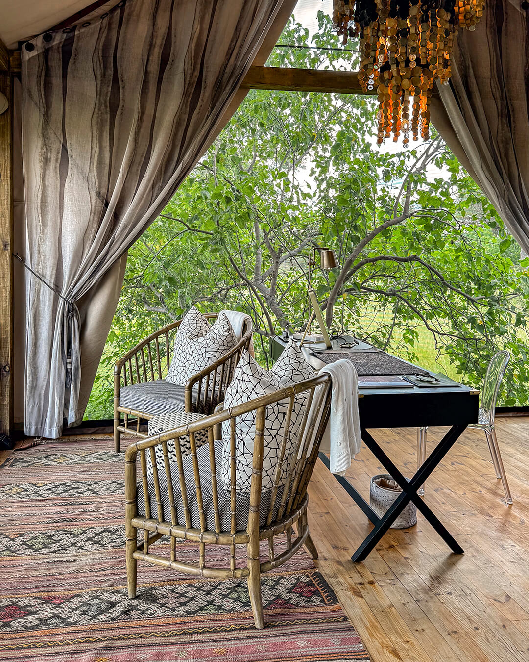 Interior de una habitación glamping en Botswana, con zona de estar, escritorio y vistas a la naturaleza