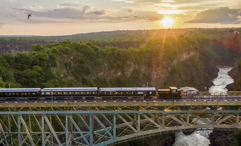 Bushtracks Express sobre el puente de Victoria Falls al atardecer, con el río Zambeze al fondo de la garganta.
