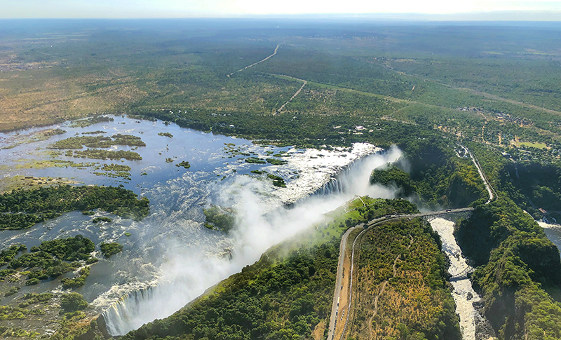 Vista aérea de las Cataratas Victoria, con las islas del Zambeze, la bruma sobre el salto y el puente junto a la garganta.